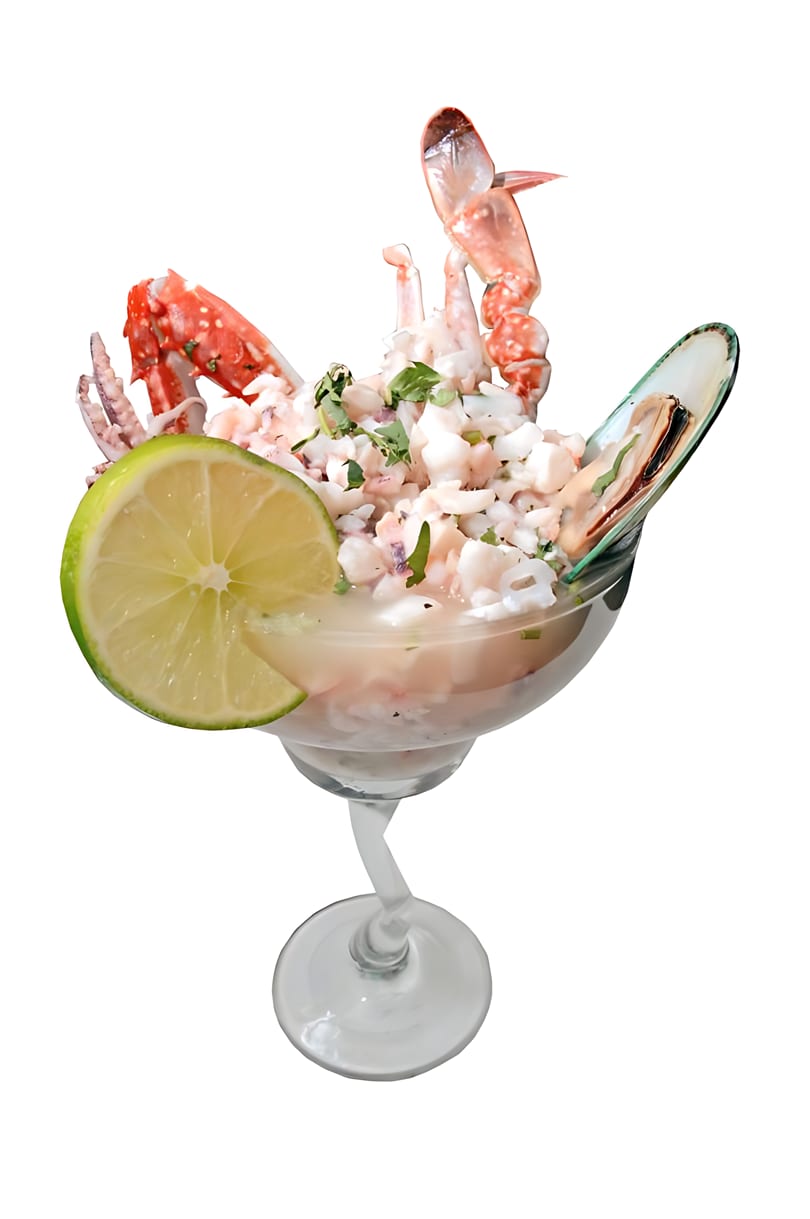 Seafood cocktail with crab legs, mussels, and lime in a margarita glass.